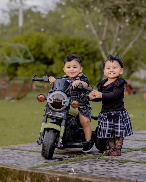 Two children posing together on a toy motorcycle